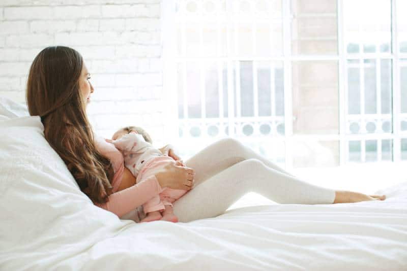 woman breastfeeding her baby on the bed