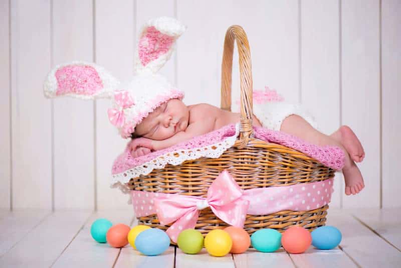 Newborn baby girl in a rabbit costume lying in a basket