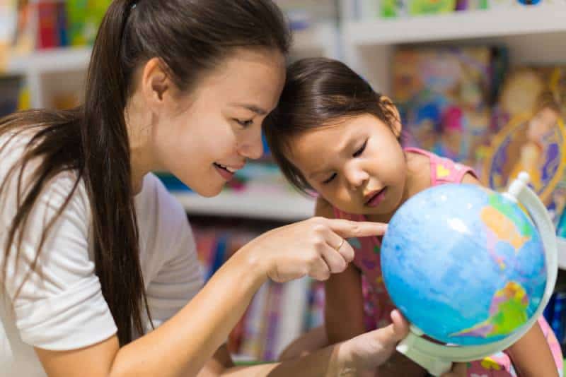 woman and daughter learning geography on a world globe