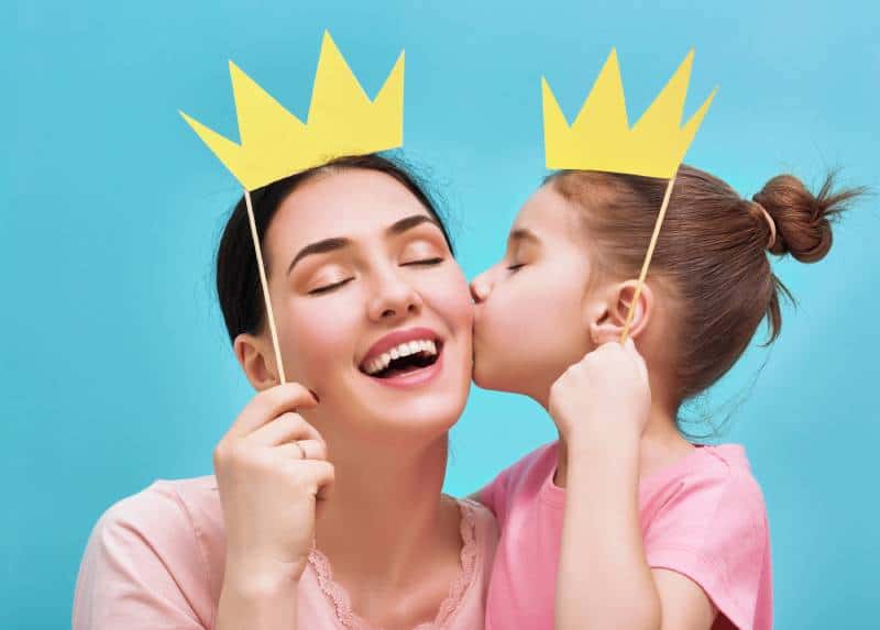 Smiling mother and daughter with paper crown props