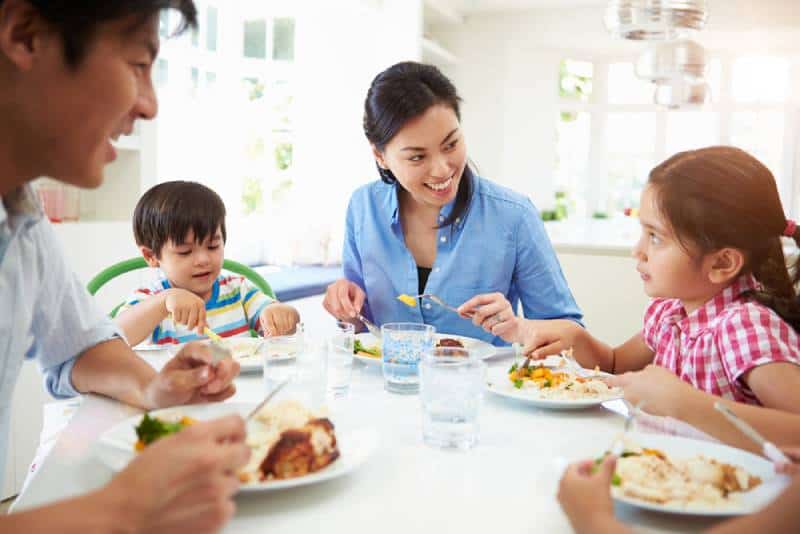 Family Sitting At Table Eating Meal Together