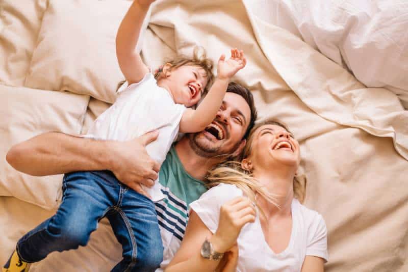 family laughing while they lie on bed