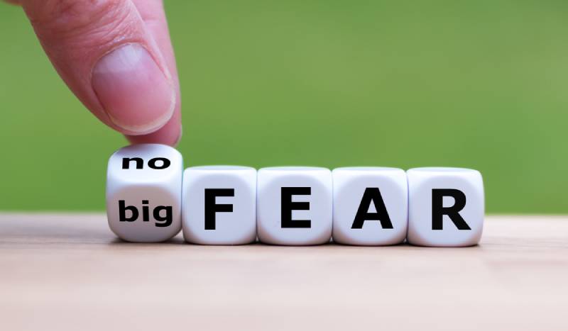 Hand turns a dice and changes the expression "big fear" to "no fear"
