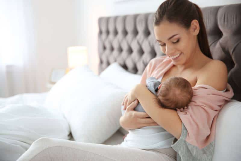 Young woman breastfeeding her baby in the bedroom