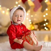 baby in christmas suit with gift