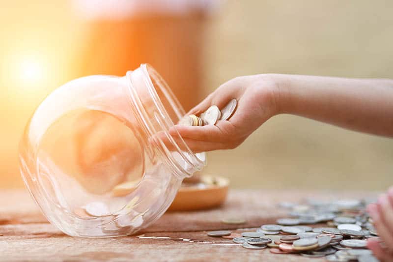 Woman's hand where she puts money in saving jar 