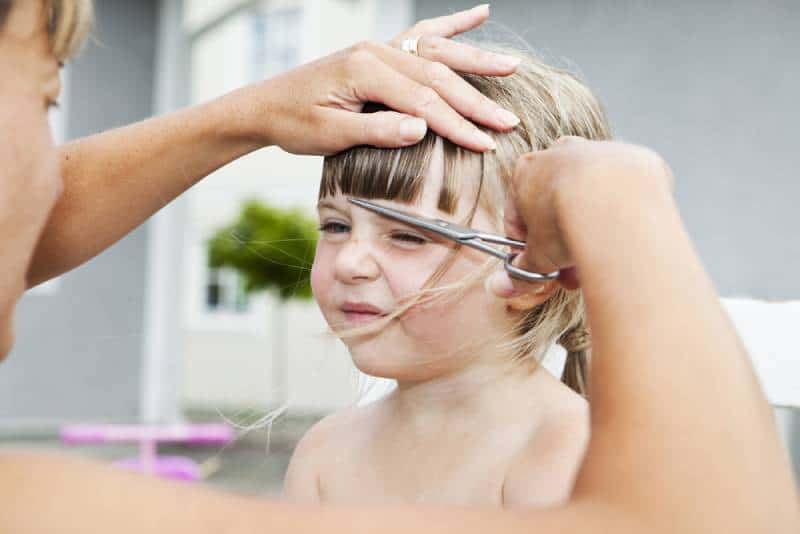 Woman cutting young girls hair