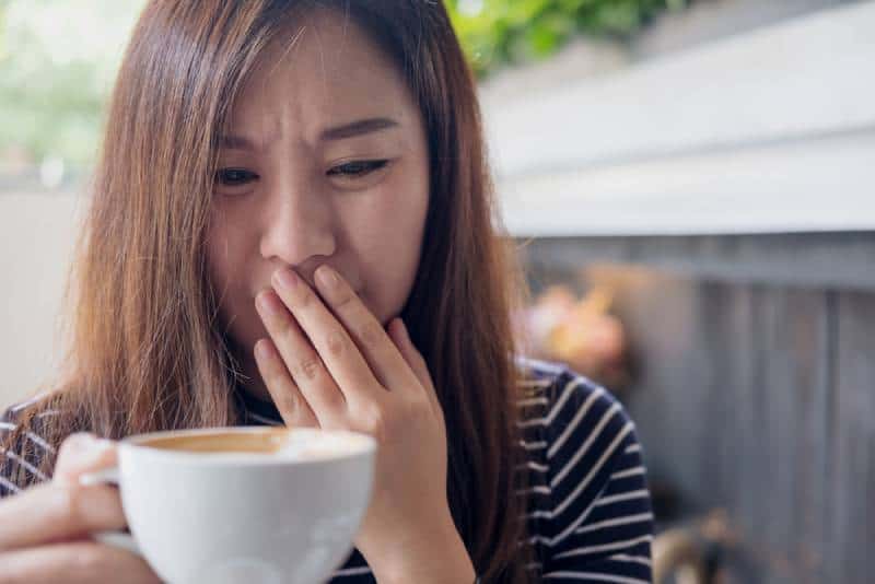woman with coffee cup and bad taste in mouth