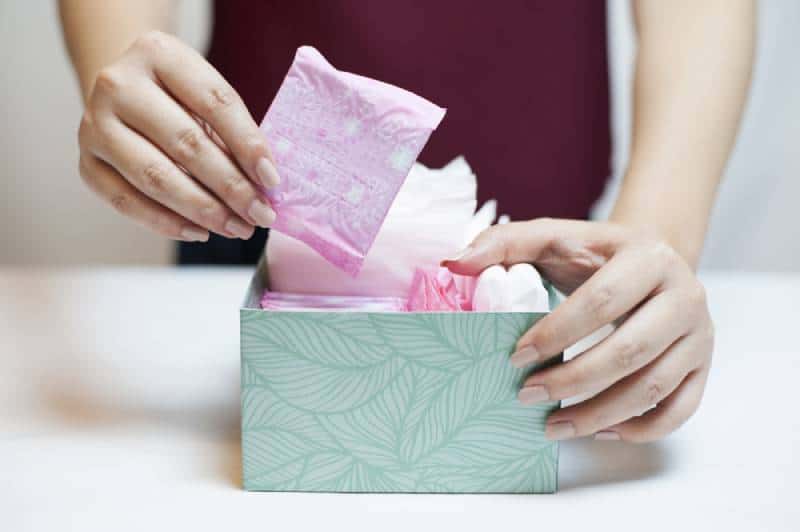 woman picking sanitary pad out of green box