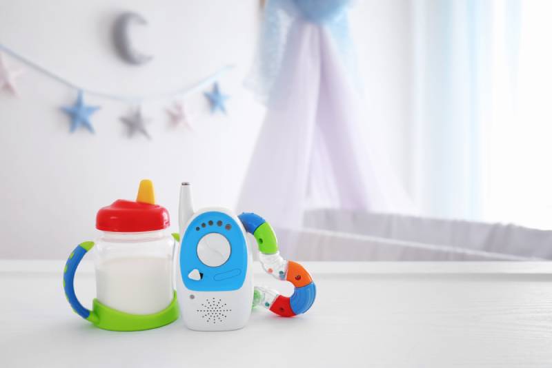 Baby monitor, rattle and sippy cup on table in room