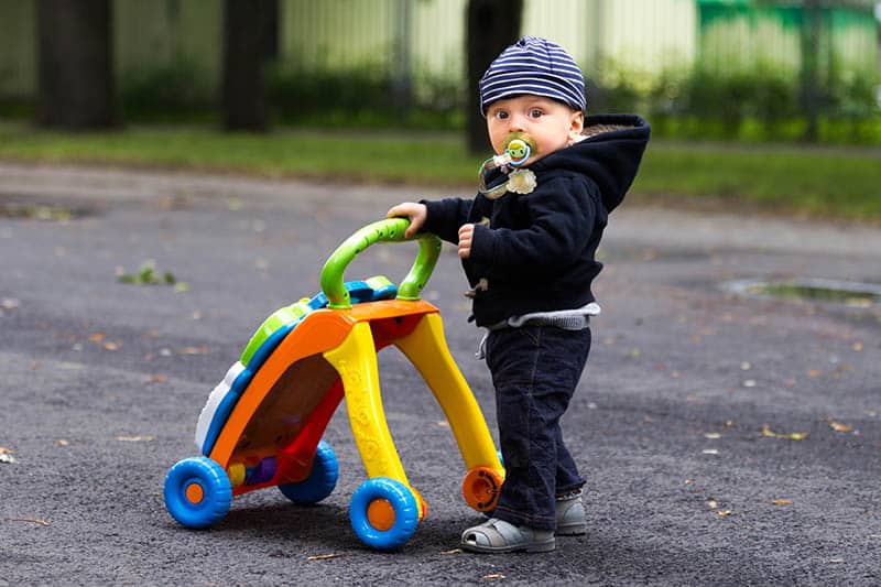cute little boy with a colorful walker outdoors