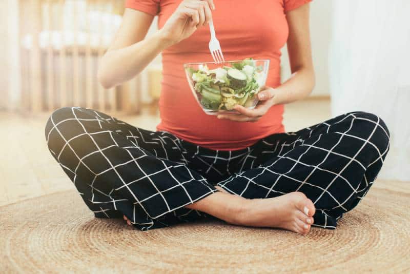 pregnant woman holding a fork and salad bowl