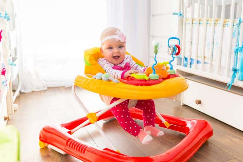First steps of the girl in a baby walker