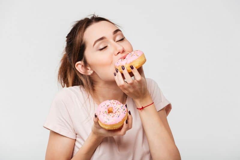 Hungry woman eating donuts