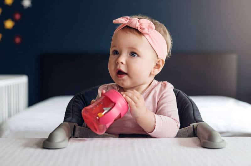 baby girl holding a sippy cup