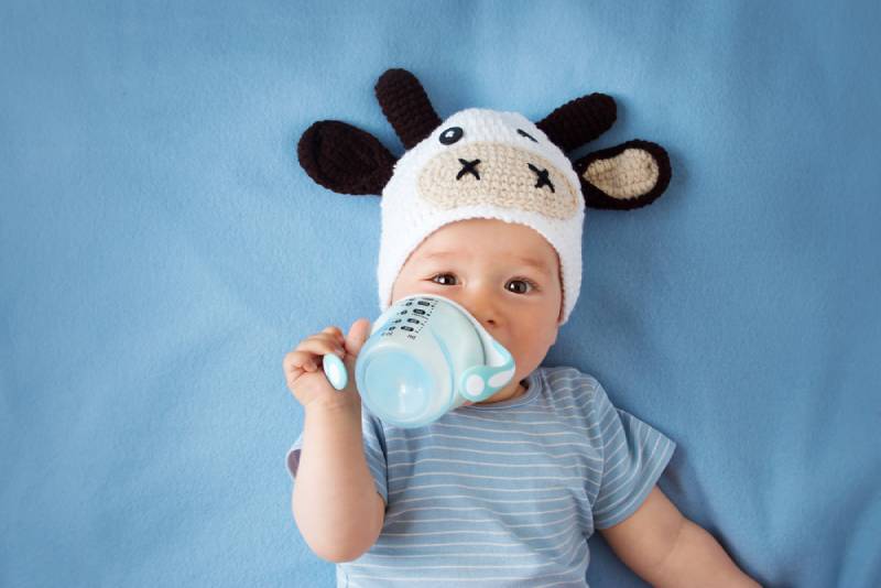 cute baby in a cow hat drinking from a sippy cup