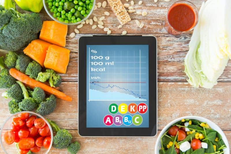 tablet with calories chart and vegetables on the table