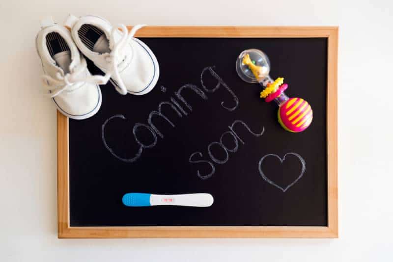Coming soon words on black chalkboard with positive pregnancy test