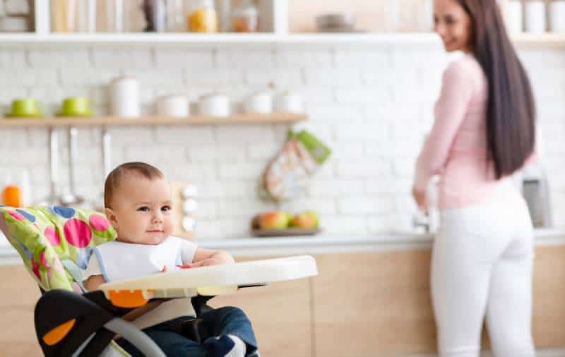baby playing on high chair in the kitchen