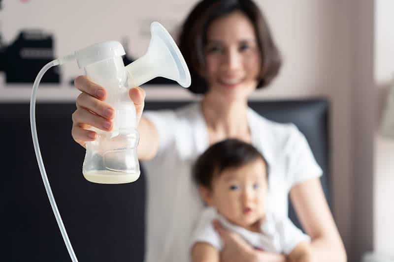 woman holding a breast pump with milk