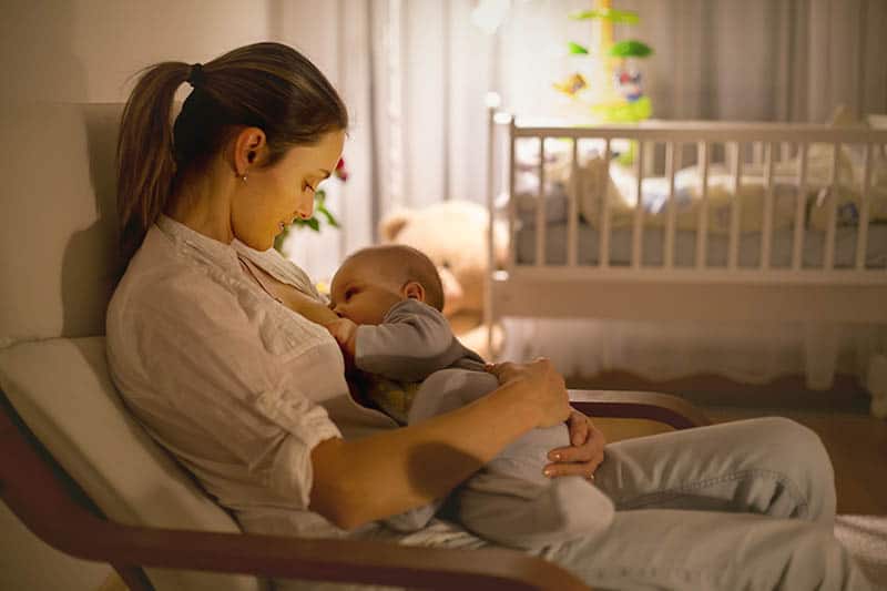 woman is breastfeeding her baby in a dark room