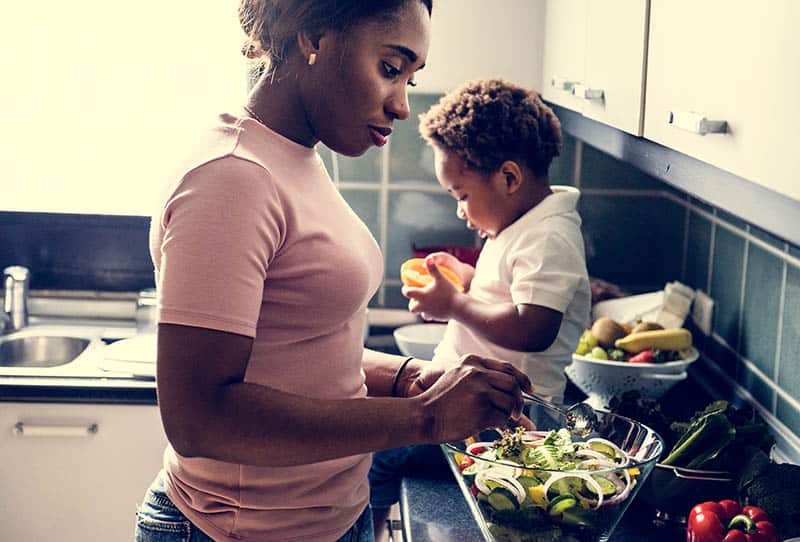 mother making salad with baby boy in the kitchen
