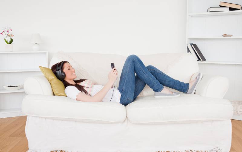 teenager listening to music with headphones while lying on a sofa