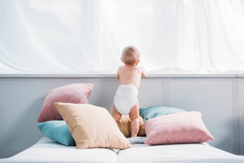 toddler standing on bed with pillows