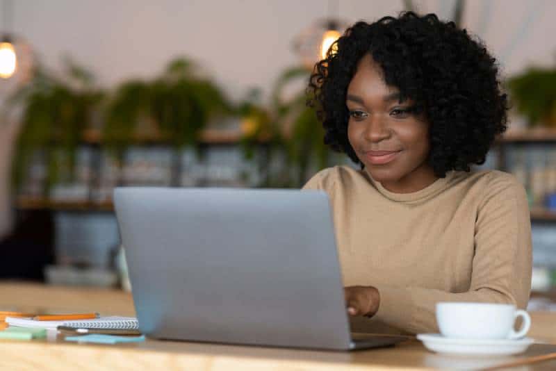 woman using laptop at home while drinking coffee