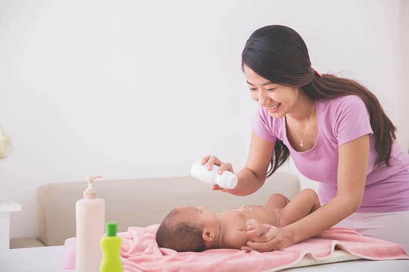 mother and baby putting baby powder