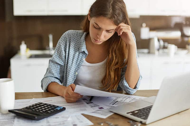 Woman sitting at the table and organizing her bills at home