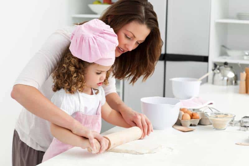 Mother and daughter using a rolling pin in the kitchen