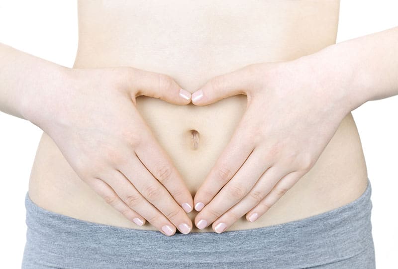 woman holding belly in heart shape for fertility 