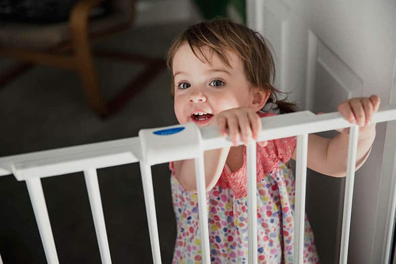 baby girl with retractable baby gate