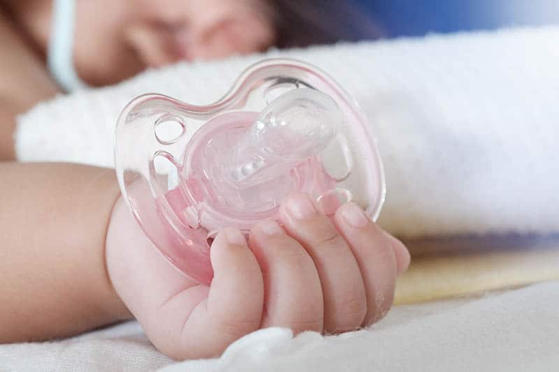 pink pacifier in baby's hand