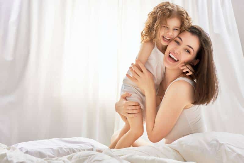 happy mother holding her child on a bed