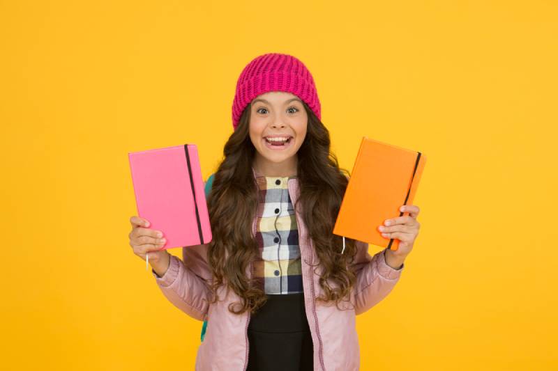 little girl holding textbooks and smiling