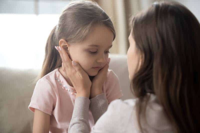 mom trying to calm down her upset daughter by talking to her