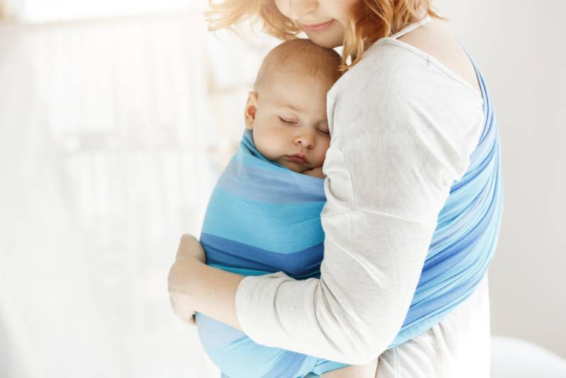 mother holding sleeping baby in baby sling