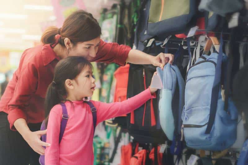 mom and little girl buying backpack