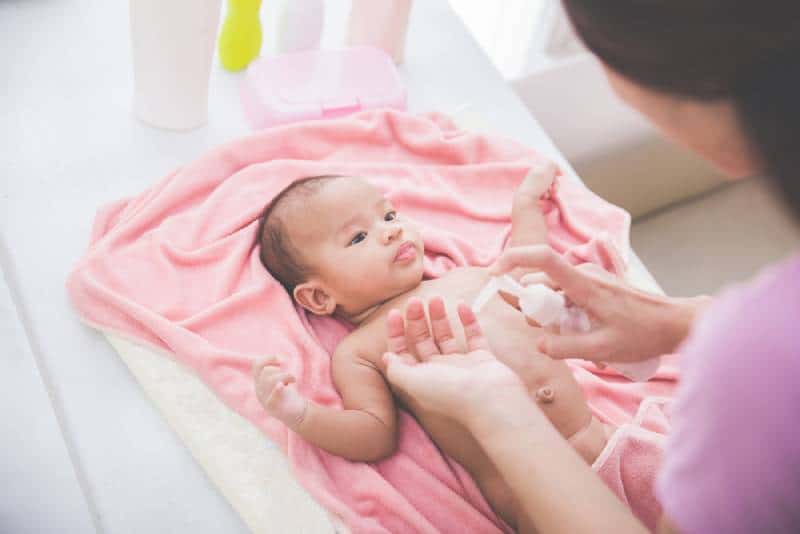 woman applying baby lotion to her baby