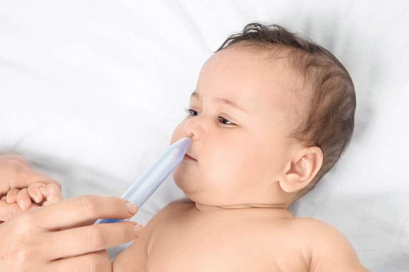 mother giving nasal aspirator to baby