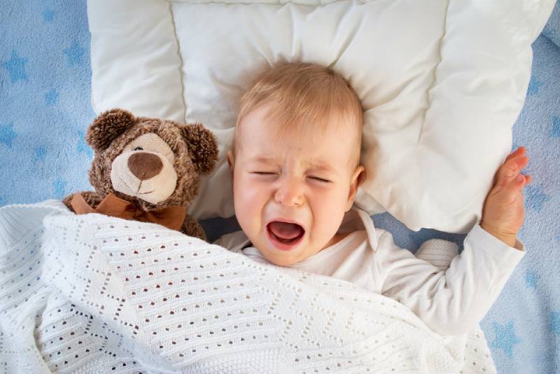 boy crying in bed with a teddy bear