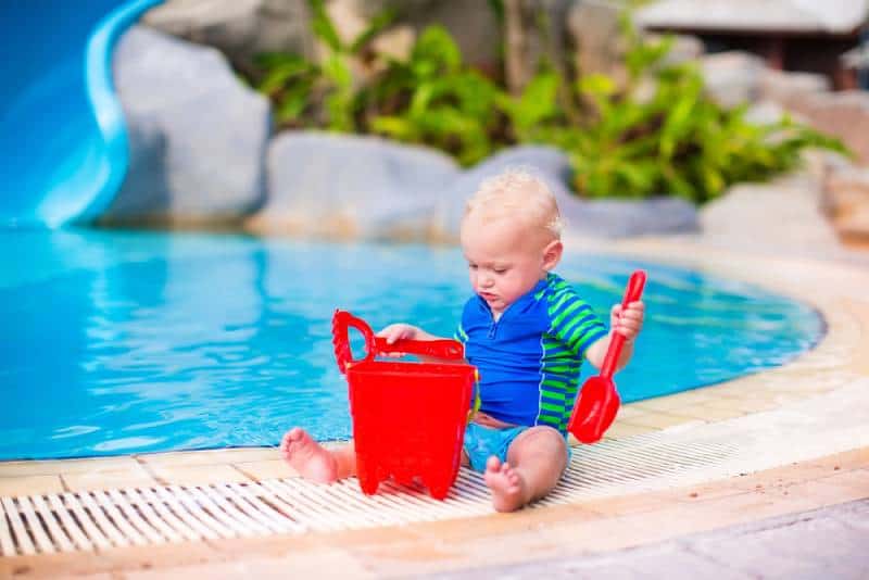 baby boy in sun protection shirt and swimming diaper playing 