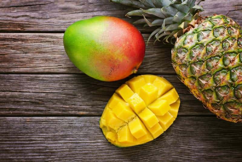 Mango with pineapple on wooden table