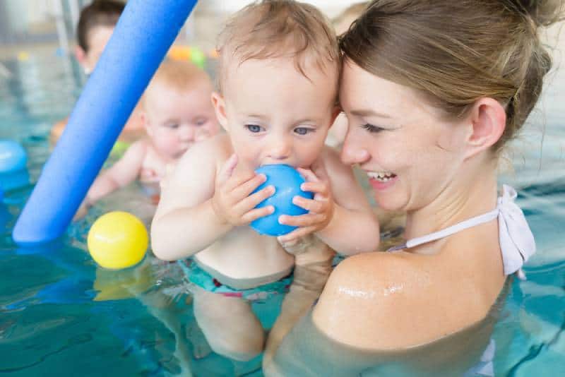 Mothers and their kids having fun at baby swimming lesson
