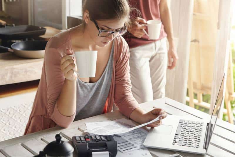 Woman taking care of the finances at her home while drinking a coffee