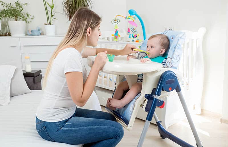 mother feeding baby in high chair