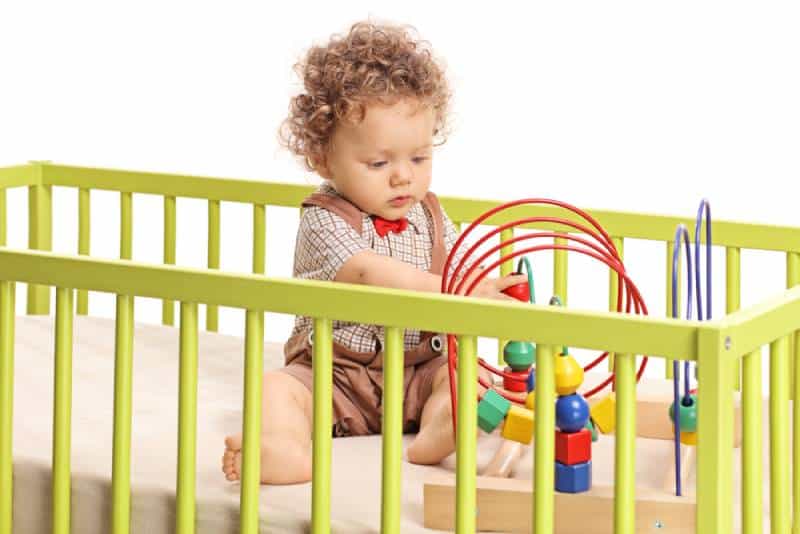 Baby boy playing with toys in a crib