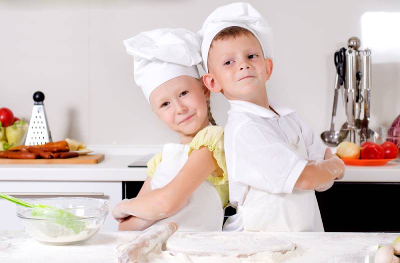 boy and girl standing back to back in the kitchen